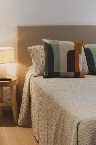 a bed with pillows and a table with a lamp at Résidence & Hôtel Aria Marina in Propriano