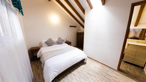 a bedroom with a white bed and a sink at ApartaHotel Margaritas de la Villa VDL in Villa de Leyva
