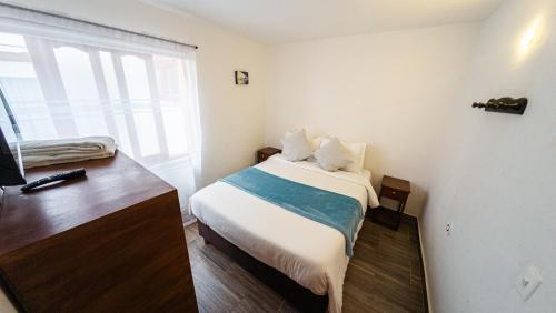 a small bedroom with a bed and a window at ApartaHotel Margaritas de la Villa VDL in Villa de Leyva