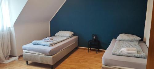 a room with two beds and a blue wall at Cozy Private Rooms in Wesseling in Wesseling