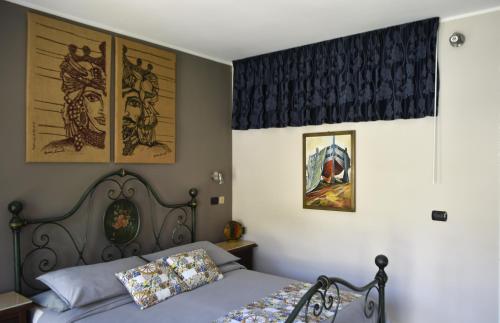 Un dormitorio con una cama y algunos cuadros en la pared. en Casa Turiddu, en Taormina