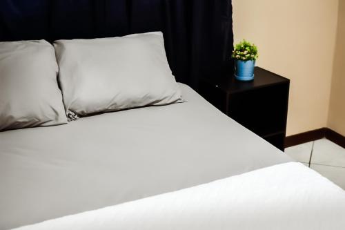 a bed with white sheets and a plant on a night stand at Apartamento completo Ideal para descansar en familia en San Salvador in San Salvador