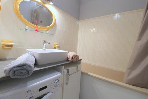 une salle de bain avec un lavabo, une baignoire et un miroir dans l'établissement Le Jardin de La Baule by Tranquil at Home, à La Baule