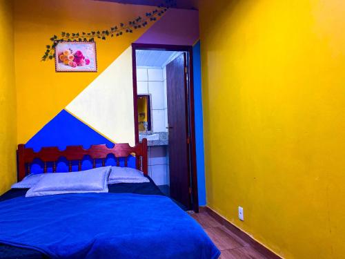 a bedroom with a blue bed in a yellow wall at Casa Luke Paraty in Paraty