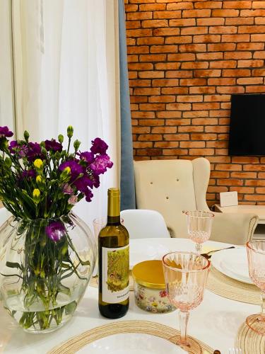 a table with a bottle of wine and purple flowers at Przytulny apartament z tarasem in Olsztynek