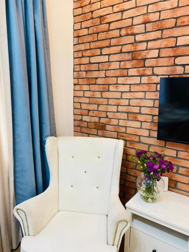 a white chair in a room with a brick wall at Przytulny apartament z tarasem in Olsztynek