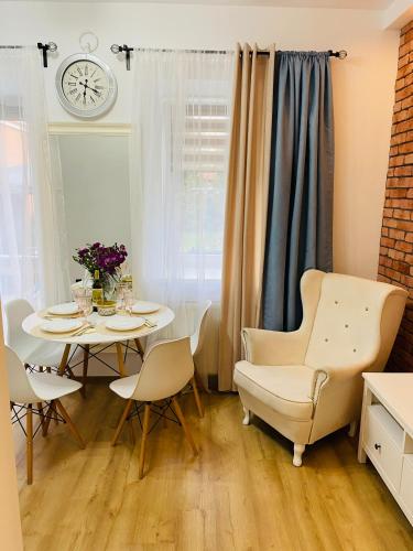a dining room with a table and chairs and a clock at Przytulny apartament z tarasem in Olsztynek