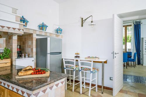 a kitchen with a counter with a refrigerator and a table at Villa De Luca - Luxury villa with terrace and Jacuzzi by the sea in Vico Equense
