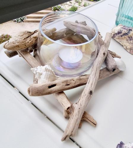 a driftwood table with a glass bowl and a candle on top at A La Plage in Leucate