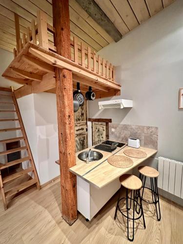 une cuisine avec un lit mezzanine et un comptoir avec tabourets dans l'établissement Agréable studio plein centre, à Saint-Gaudens