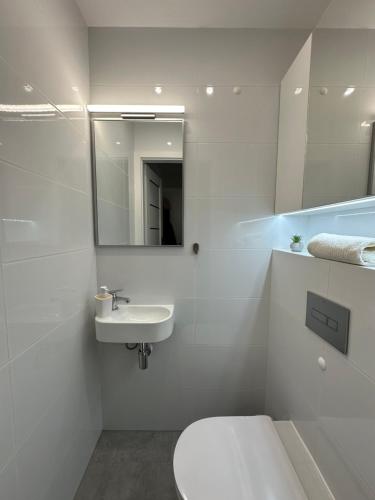a white bathroom with a toilet and a sink at Studio z sypialnią na Zatorzu in Słupsk