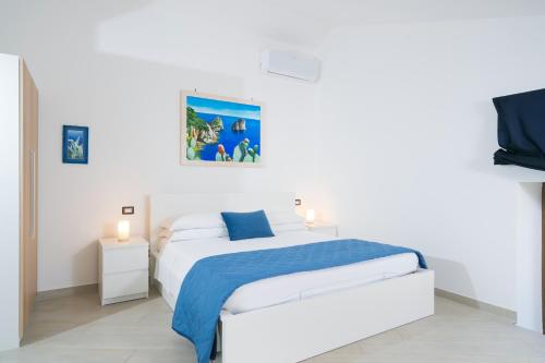 a white bedroom with a bed and a tv at Villa De Luca - Luxury villa with terrace and Jacuzzi by the sea in Vico Equense