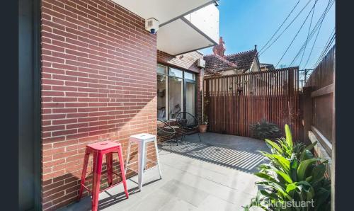 a patio with two stools and a brick wall at Unit 3 23 Foster Street St Kilda in Melbourne