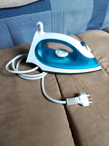 a blue and white iron sitting on top of a bed at Casa Ampla em Boituva-SP in Boituva