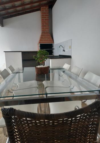 a glass table with chairs and a plant on it at Casa Ampla em Boituva-SP in Boituva