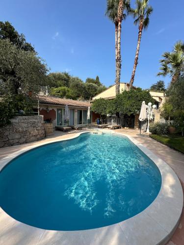 une grande piscine bleue avec des palmiers et une maison dans l'établissement Villa Miron, à Menton
