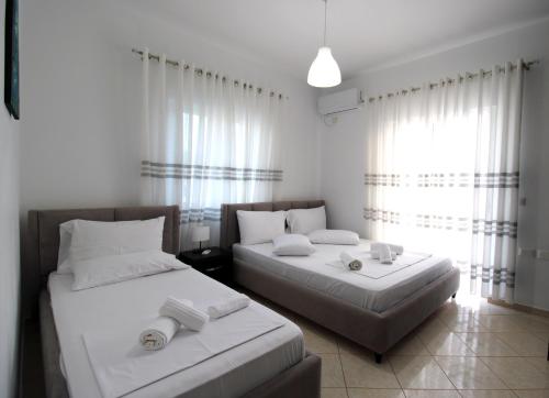 a bedroom with two beds with white sheets at Omnia Apartments in Ksamil