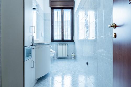a white bathroom with a toilet and a window at Luxe Apartment near Milano, Rho Fiera e MXP in Busto Arsizio