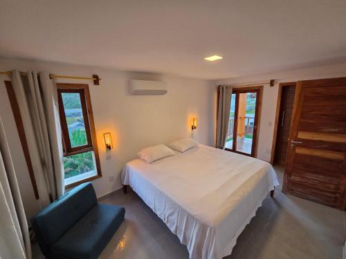 a bedroom with a white bed and a blue chair at Casa Ilhéus in Ilhéus
