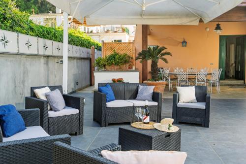 a patio with chairs and tables and an umbrella at Villa De Luca - Luxury villa with terrace and Jacuzzi by the sea in Vico Equense