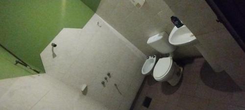 Un baño con dos inodoros en tonos verde y blanco. en Hospedaje24hs, en Argentina