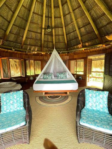 two wicker chairs and a bed in a hut at Ecohabs Tequendama - Parque Tayrona in El Zaino