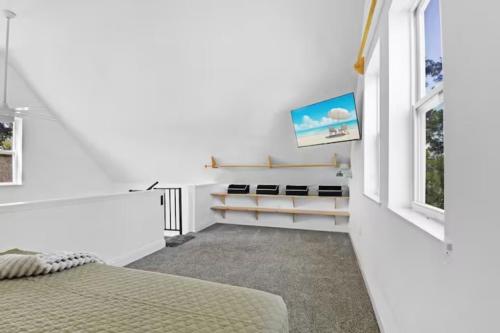 a white bedroom with a bed and a tv at Anastasia Island Treehouse in St. Augustine