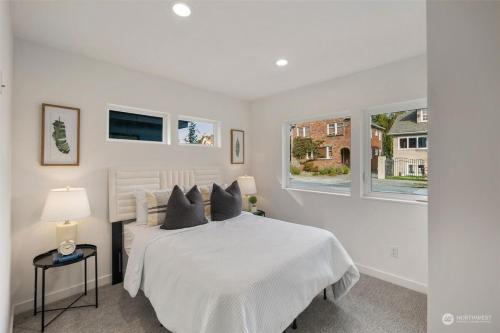 a white bedroom with a bed and two windows at Alki Beach Front TownHome in Seattle