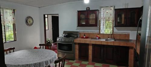a kitchen with a table and a sink and a stove at Casa Posada Margarita in Bijagua