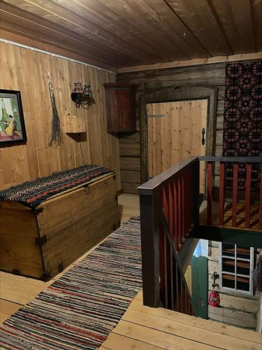 a room with a bed and a staircase in a cabin at Koselig tømmerhus på gammel gård i Skåbu in Graupe