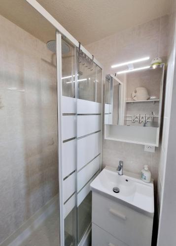 a white bathroom with a sink and a mirror at A La Plage in Leucate