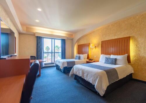 a hotel room with two beds and a large window at Hotel Flamingo Inn in Querétaro