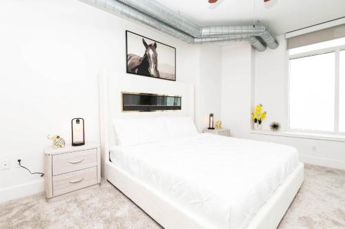 a white bedroom with a large white bed and a window at Sky-Rise Apartments in Los Angeles