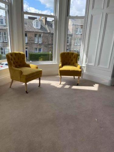 two yellow chairs sitting in a room with windows at Kingston Guesthouse in Edinburgh