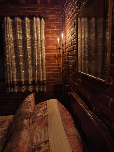 a bedroom with a bed and a brick wall at Pousada Romântica Serra da Mata in Penedo