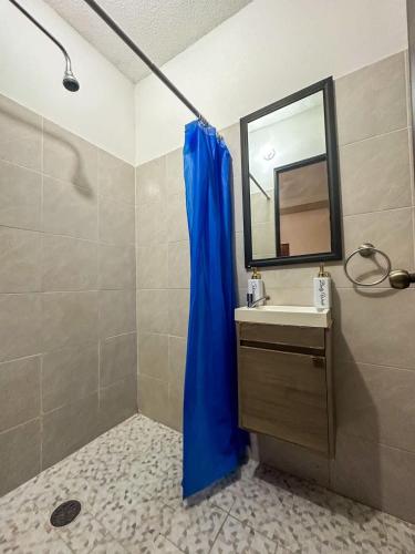 a bathroom with a blue shower curtain and a sink at Increible Loft con piscina 3 personas Casa Montes in Mérida