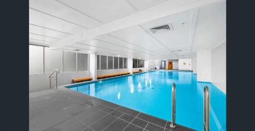 a large swimming pool with blue water in a building at Entire Apartment in Zetland in Sydney