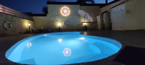 a large blue pool in a courtyard at night at Pool Seaside Relais - VILLE Ninfea, Marea, Rosa e Cassiopea in Fontane Bianche