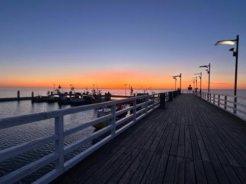 a wooden pier with a sunset on the water at Seaside Chill in Mechelinki