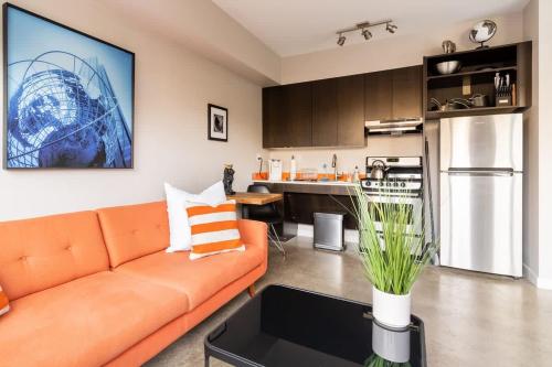 a living room with an orange couch and a kitchen at Bright Studio Apartment - Food Carts & Local Shops in Portland