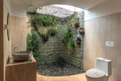 a bathroom with a stone wall with plants on the wall at Villa Sande in Munduk