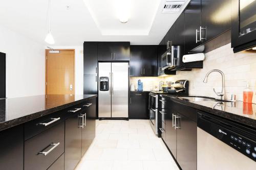 a kitchen with black cabinets and a stainless steel refrigerator at Sky-Rise Apartments in Los Angeles