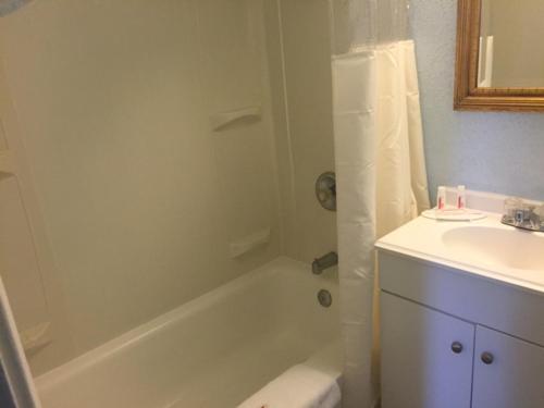 a bathroom with a white tub and a sink at Days Inn by Wyndham Cleveland Lakewood in Lakewood