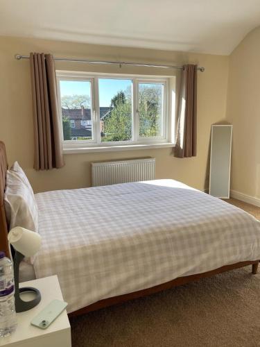 a bedroom with a large bed and two windows at Spacious 3 bed with driveway in Manchester