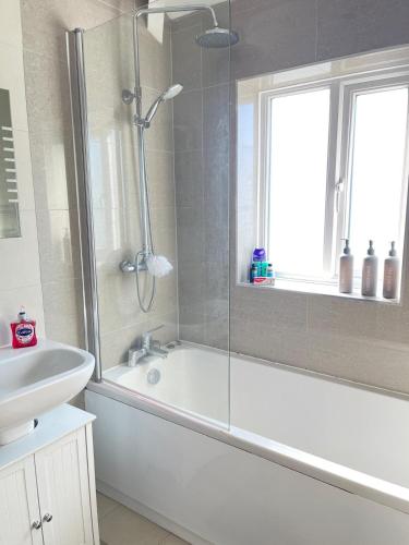 a bathroom with a shower and a tub and a sink at Spacious 3 bed with driveway in Manchester