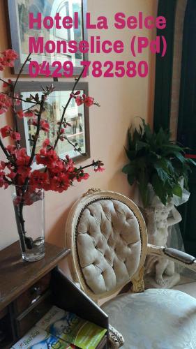 a room with a chair and a vase with flowers at Hotel La Selce in Monselice
