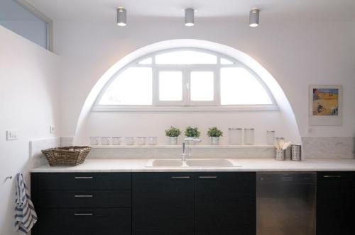 a kitchen with a sink and an arch window at Beautiful Oia Villa in Oia