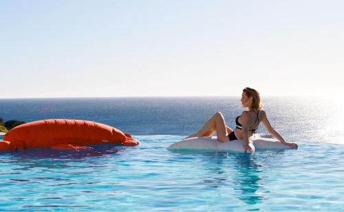 une femme en bikini assise sur un radeau dans l'eau dans l'établissement Holiday Paradise, à Cannes