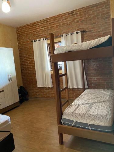 a bedroom with two bunk beds and a brick wall at Cantinho rústico com piscina privativa em Brotas SP in Brotas