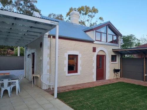 a small house with a patio and a table at 1860 Heritage Beachside Studio in Somerton Park